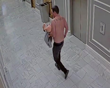A shirtless man carries a flamingo in a hallway