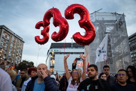 Group of people holding red balloons shaped like the number three during a demonstration